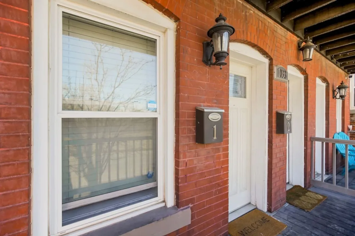This image captures a welcoming front porch with dual front doors, a welcome mat, and lanterns, creating an inviting first impression and showcasing a comfortable entryway into the home.