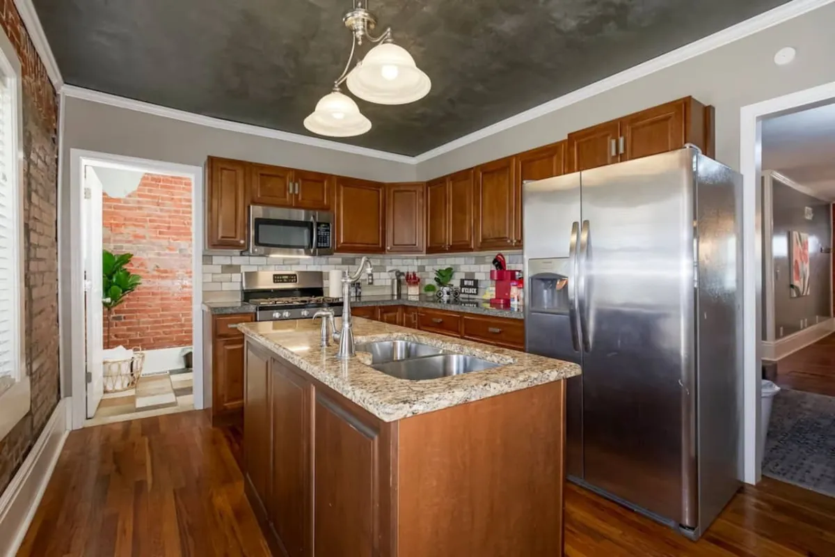 A modern, fully equipped kitchen with granite countertops, stainless steel appliances, and wooden cabinets. The layout is perfect for preparing daily meals and enjoying the freedom of home cooking during extended visits.